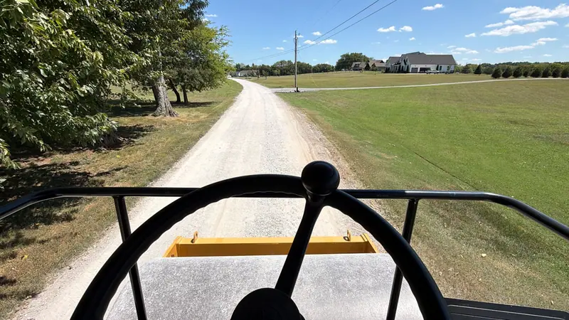 View from a tracked loader cab down a freshly graded gravel driveway