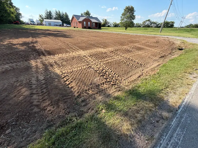 Graded lot beside a country road with a brick house behind